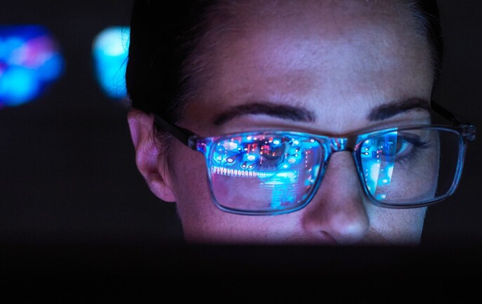 A woman wearing glasses is looking at a computer screen